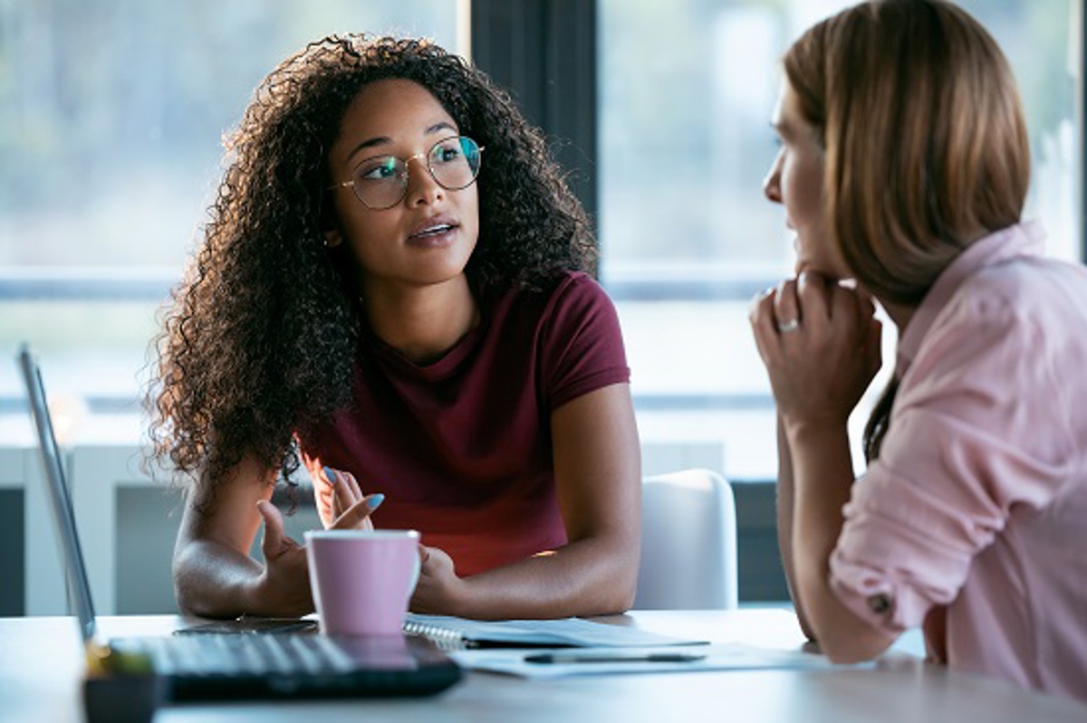Two Women Talking At A Desk