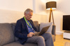 A man sitting down on a couch with a laptop