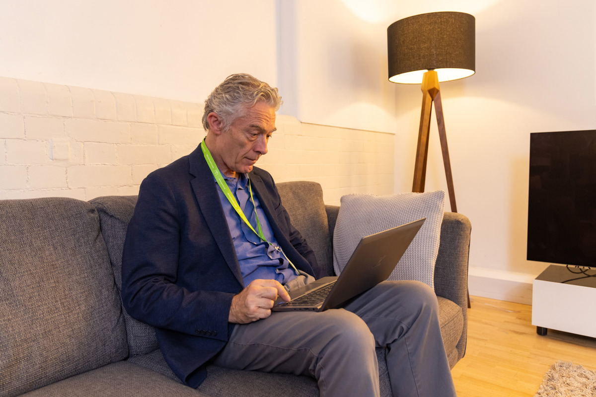 A man sitting down on a couch with a laptop