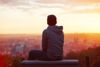 A Man Sitting Down And Looking At A Sunrise