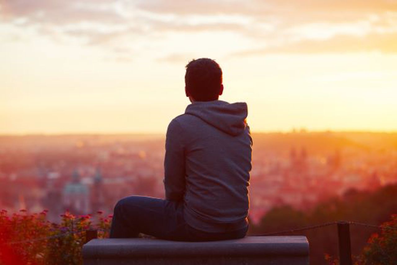 A Man Sitting Down And Looking At A Sunrise