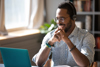 A man smiling working on a laptop