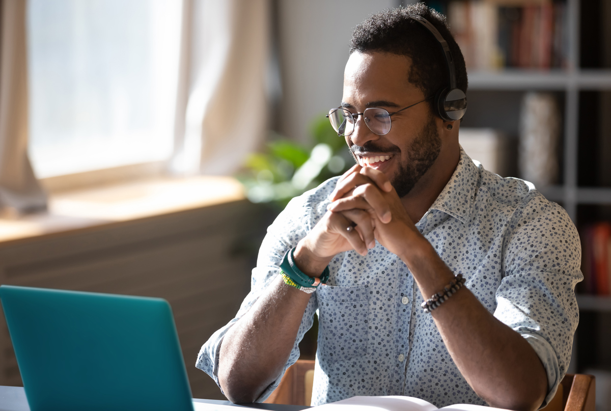 A man smiling working on a laptop