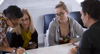 Four People Around A Table Looking Down At A Graph